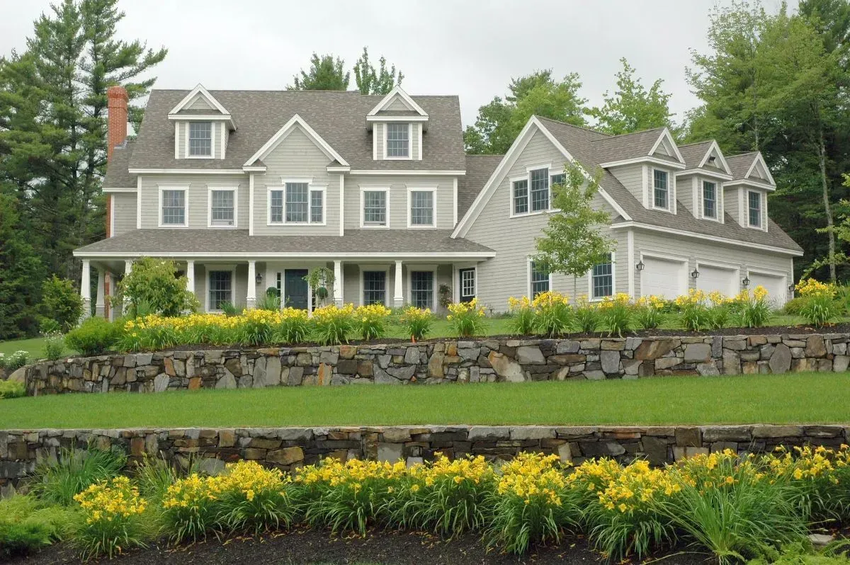 A large house with a stone wall in front of it