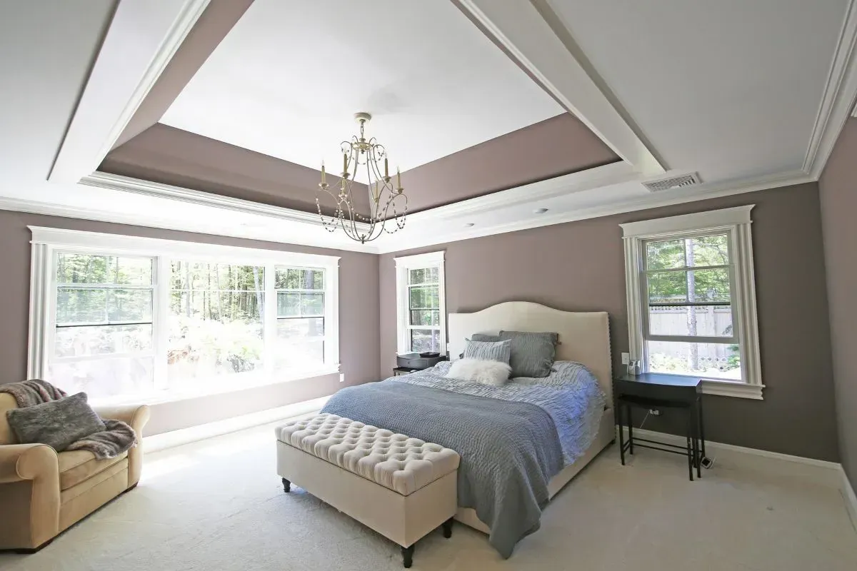 Custom design ceiling with inset chandelier in this bedroom.