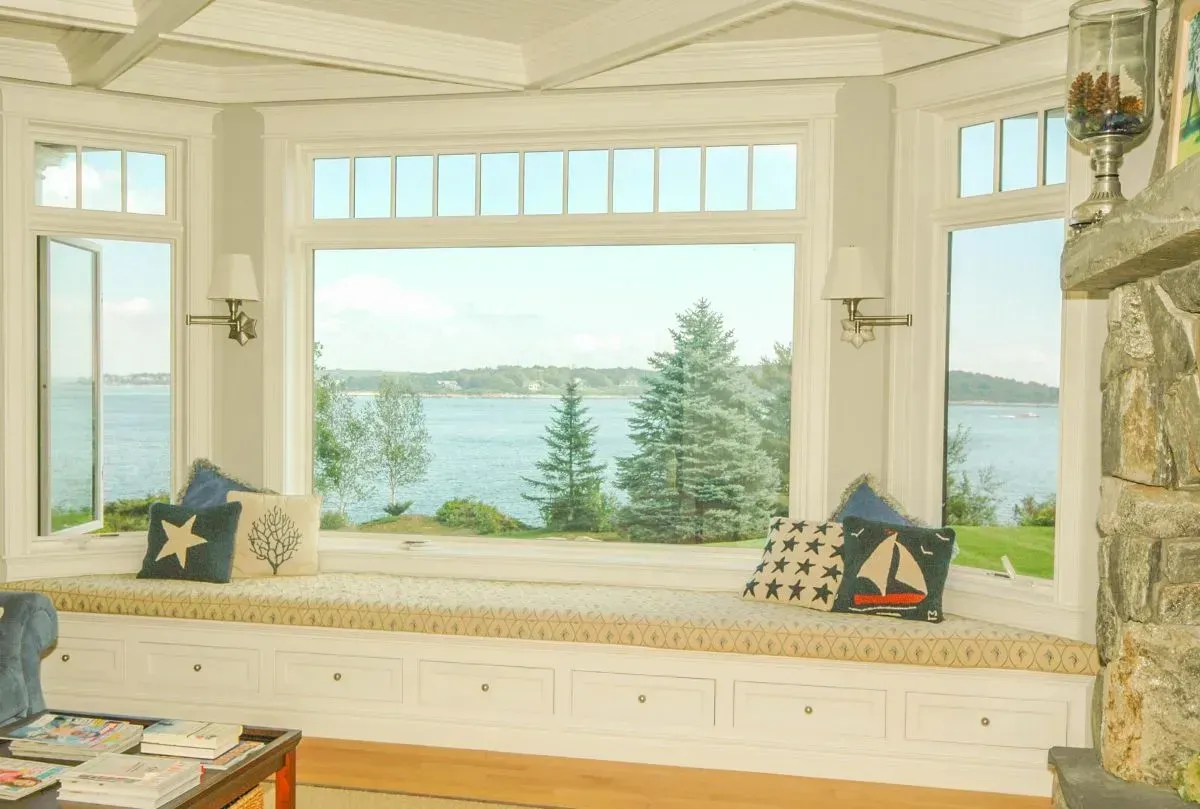 A living room with a bay window with a view of the ocean.
