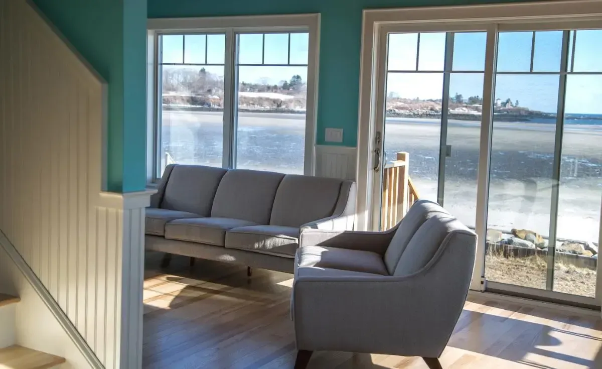 A living room with a couch and chair and a view of the ocean