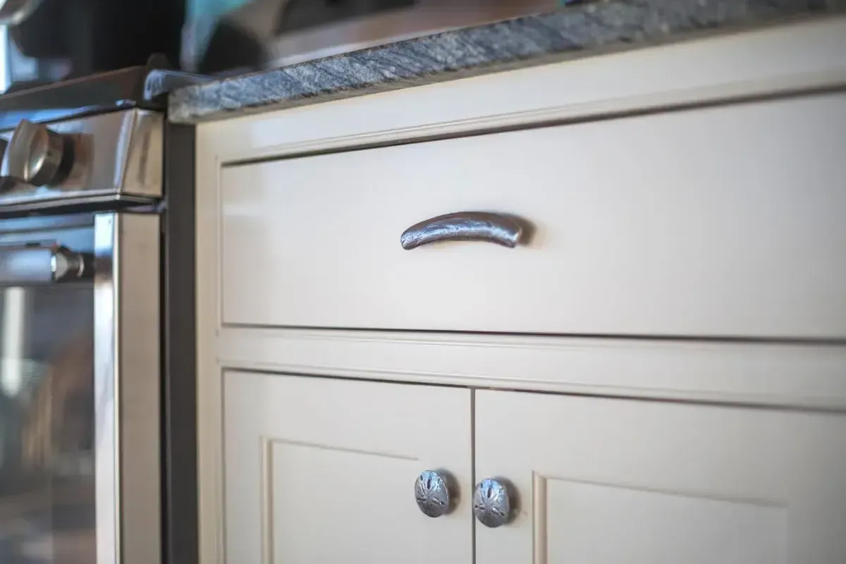 A close up of a kitchen cabinet with a stove in the background.