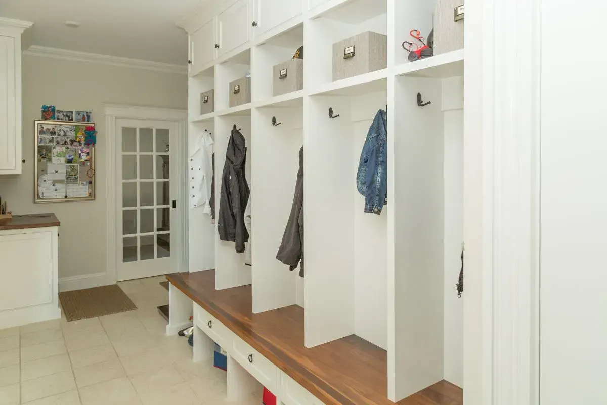 custom built entryway white cubbies, five in a row with hanging jackets. 
