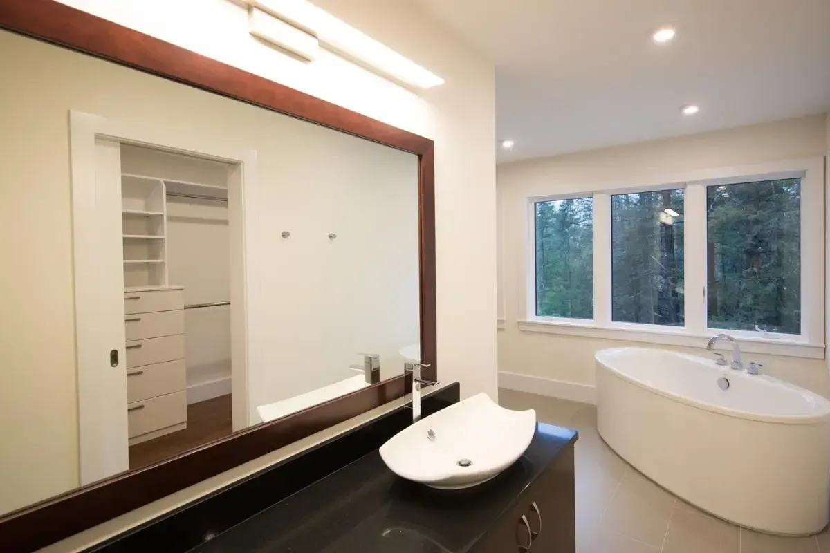 A bathroom with a large mirror a sink and a bathtub