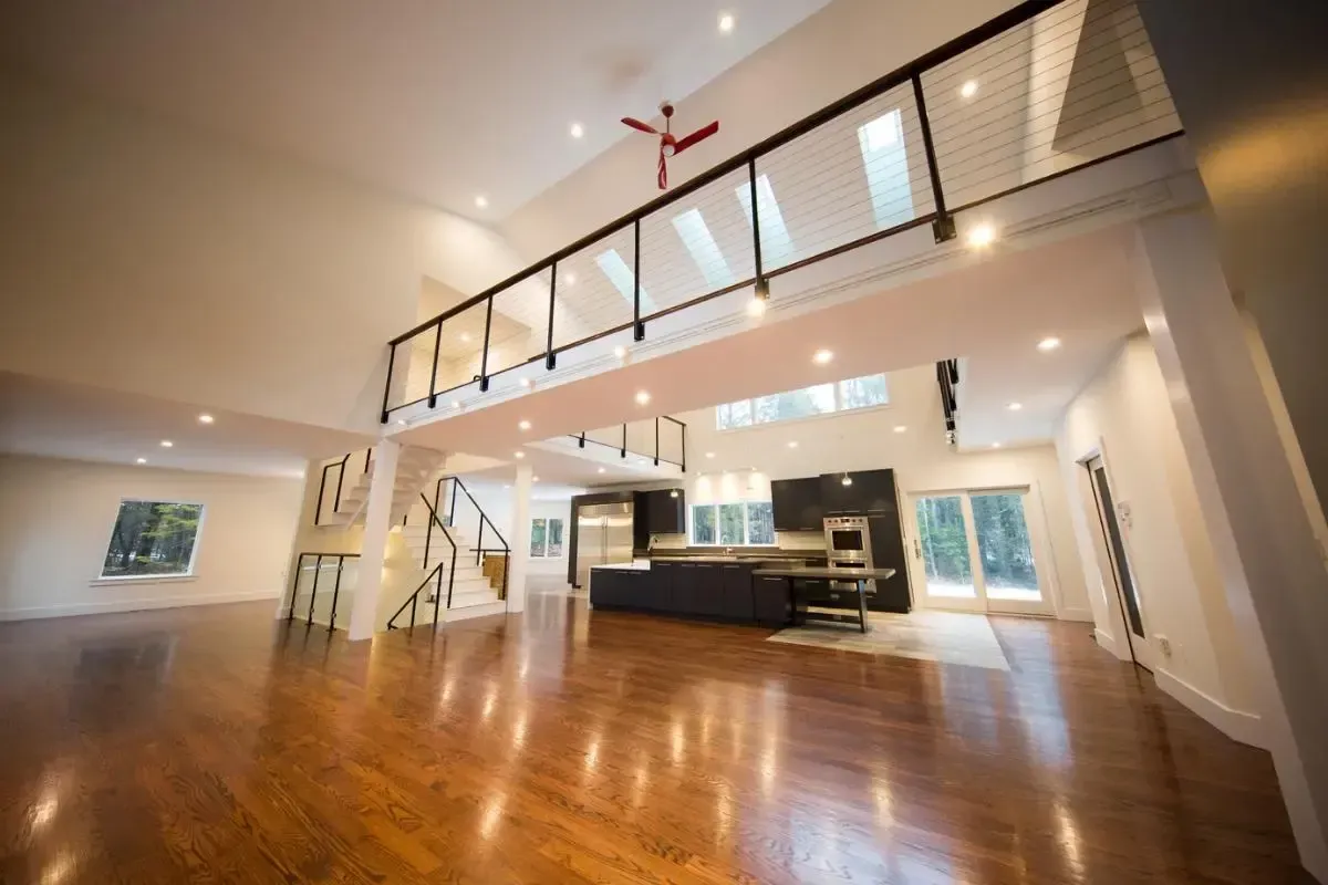 A large empty room with hardwood floors and a balcony.