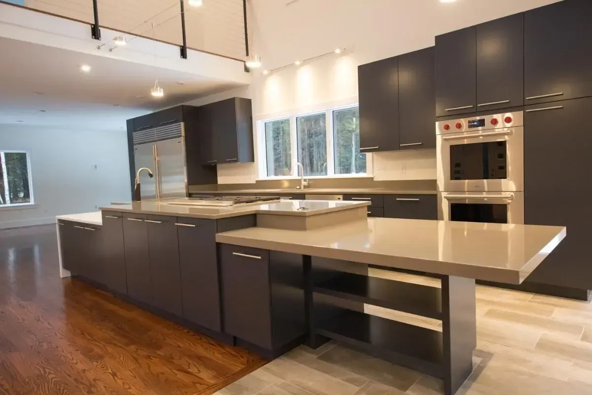 A kitchen with black cabinets , stainless steel appliances , and a large island.