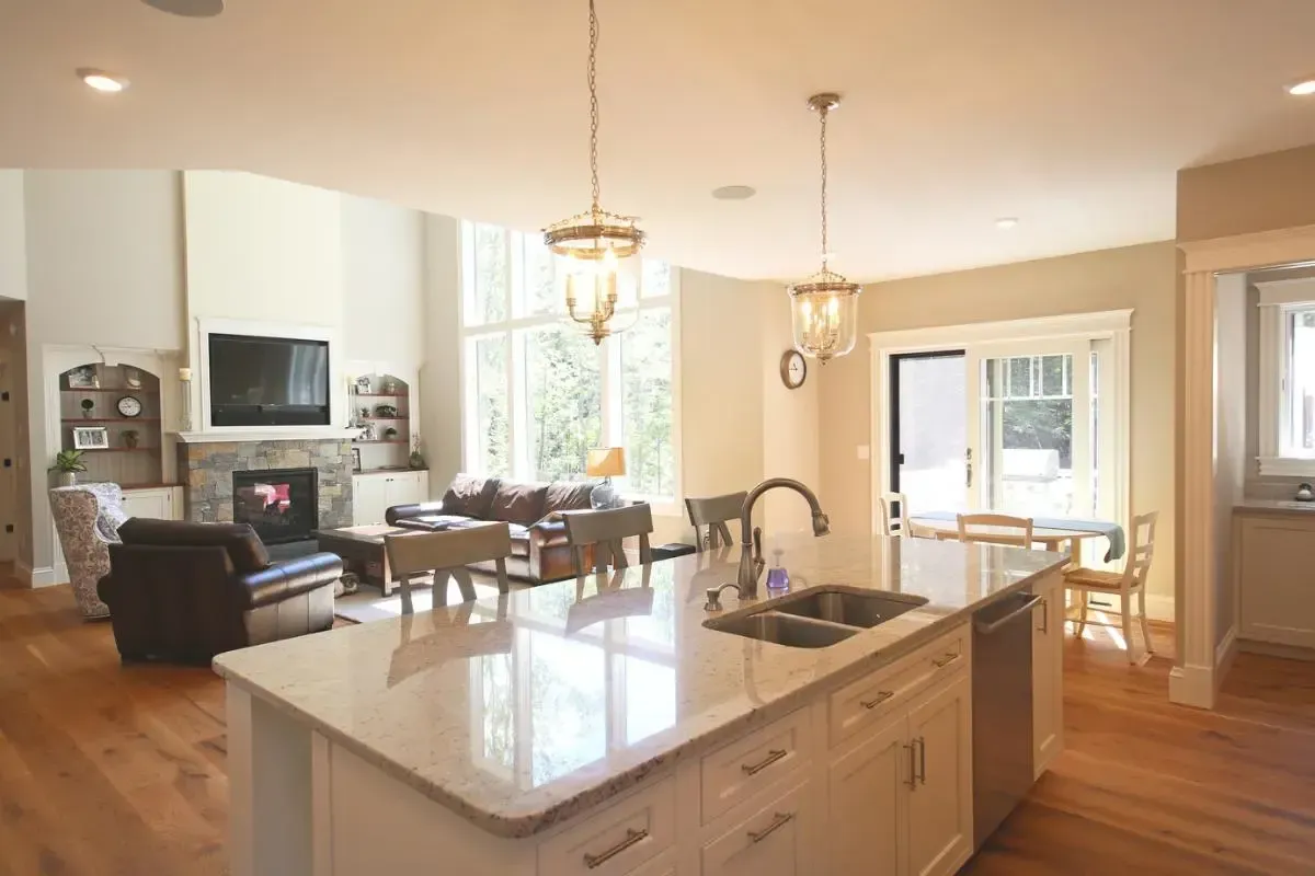 A kitchen with a sink and a fireplace in a living room.