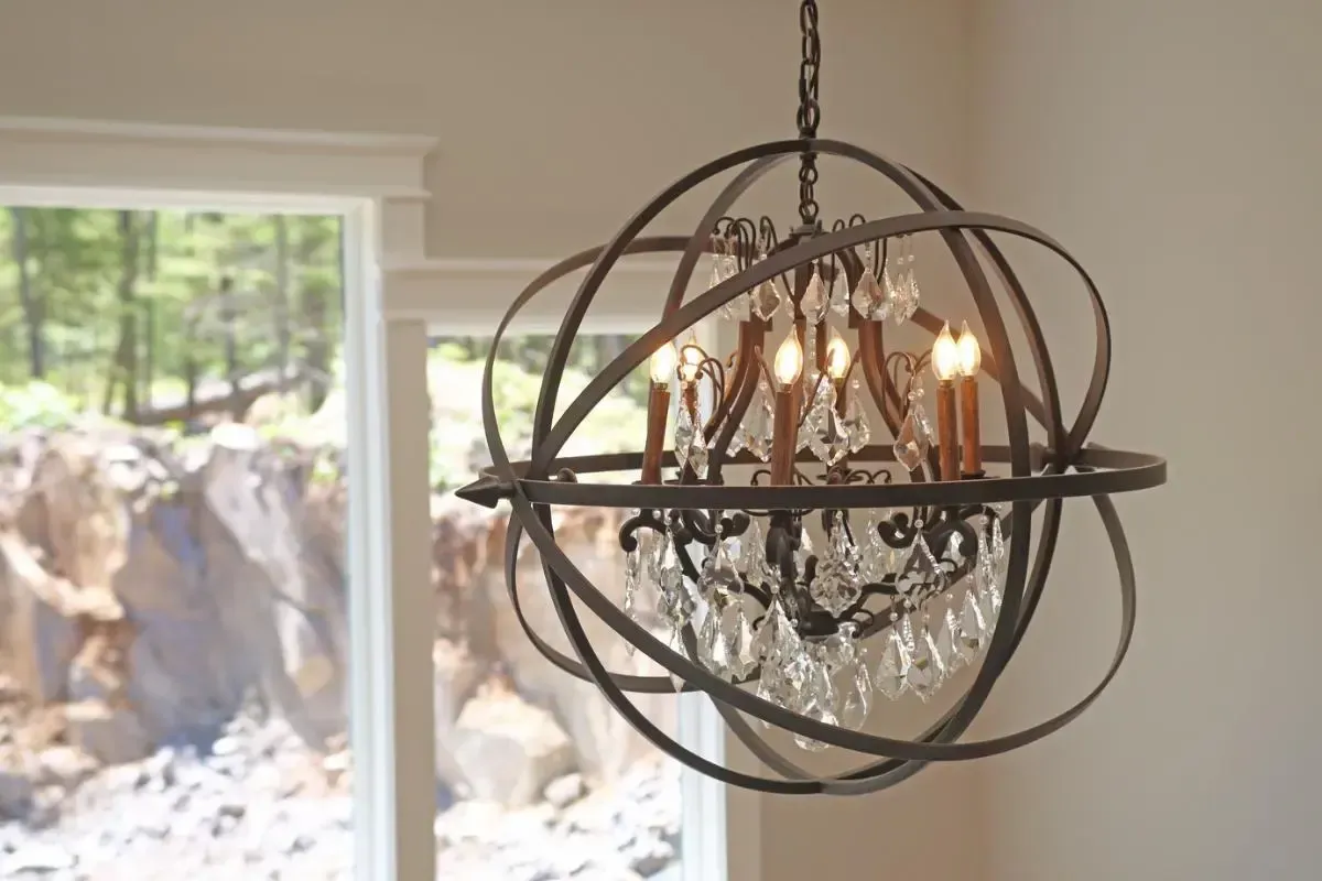 A chandelier is hanging from the ceiling in front of a window.