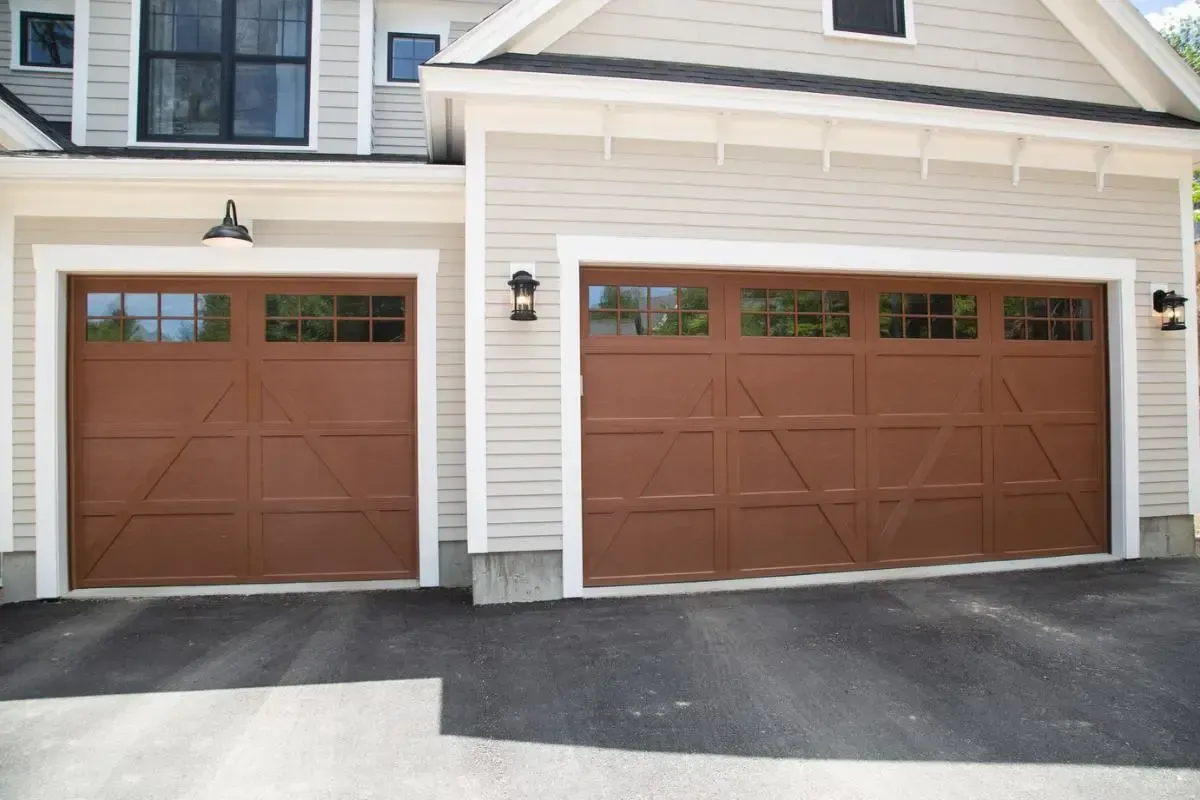 Two brown garage doors are on the side of a house