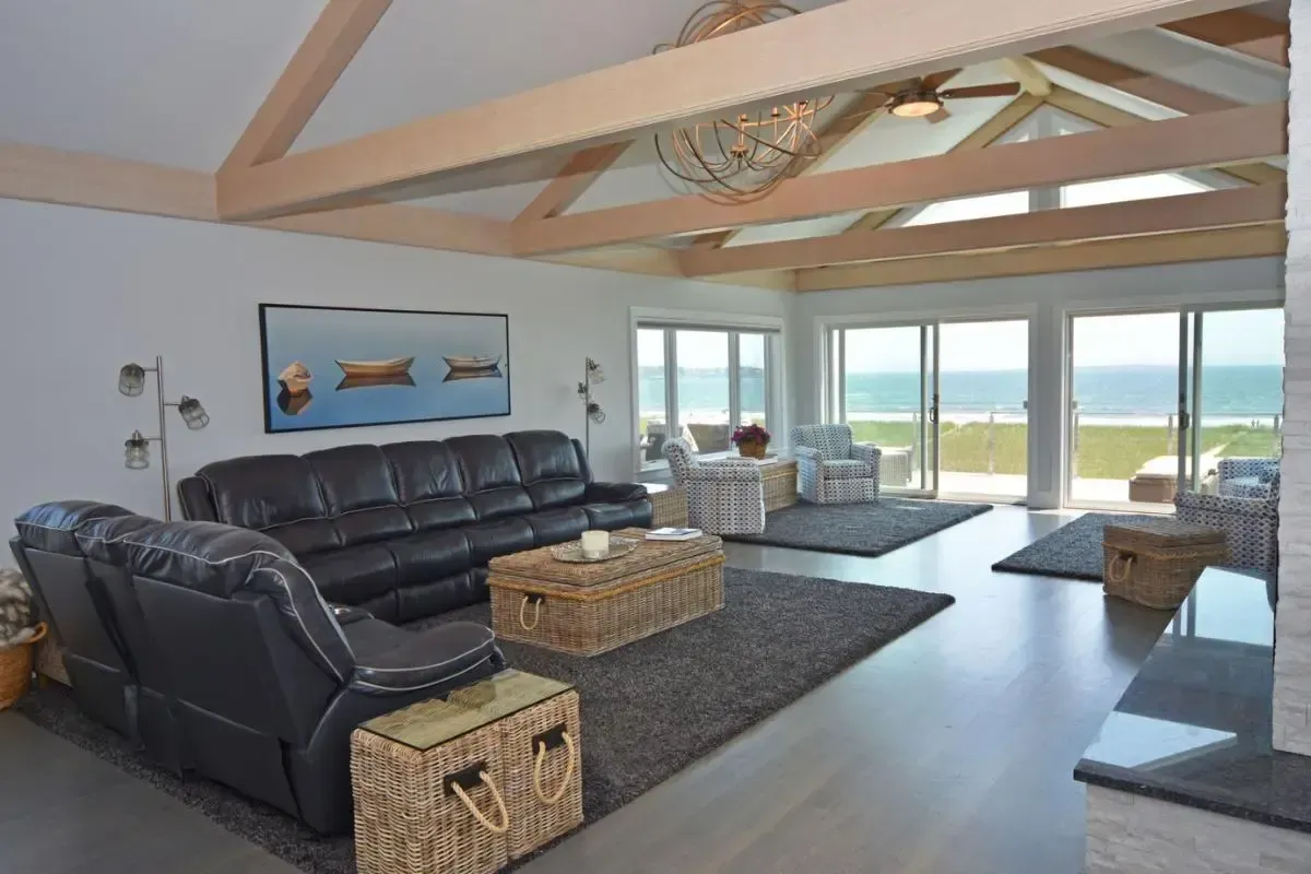 A living room with a couch , chairs , and a table with a view of the ocean.