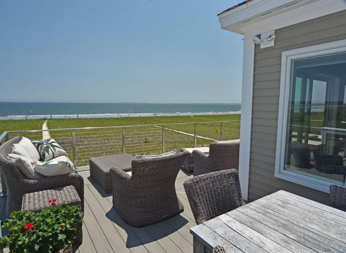 A deck with chairs and a table overlooking the ocean