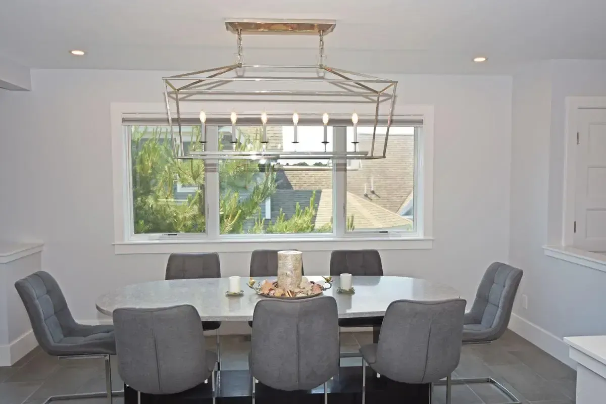 A dining room with a table and chairs and a large window.