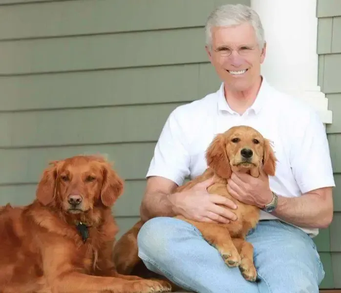 A man is sitting on a porch with two dogs