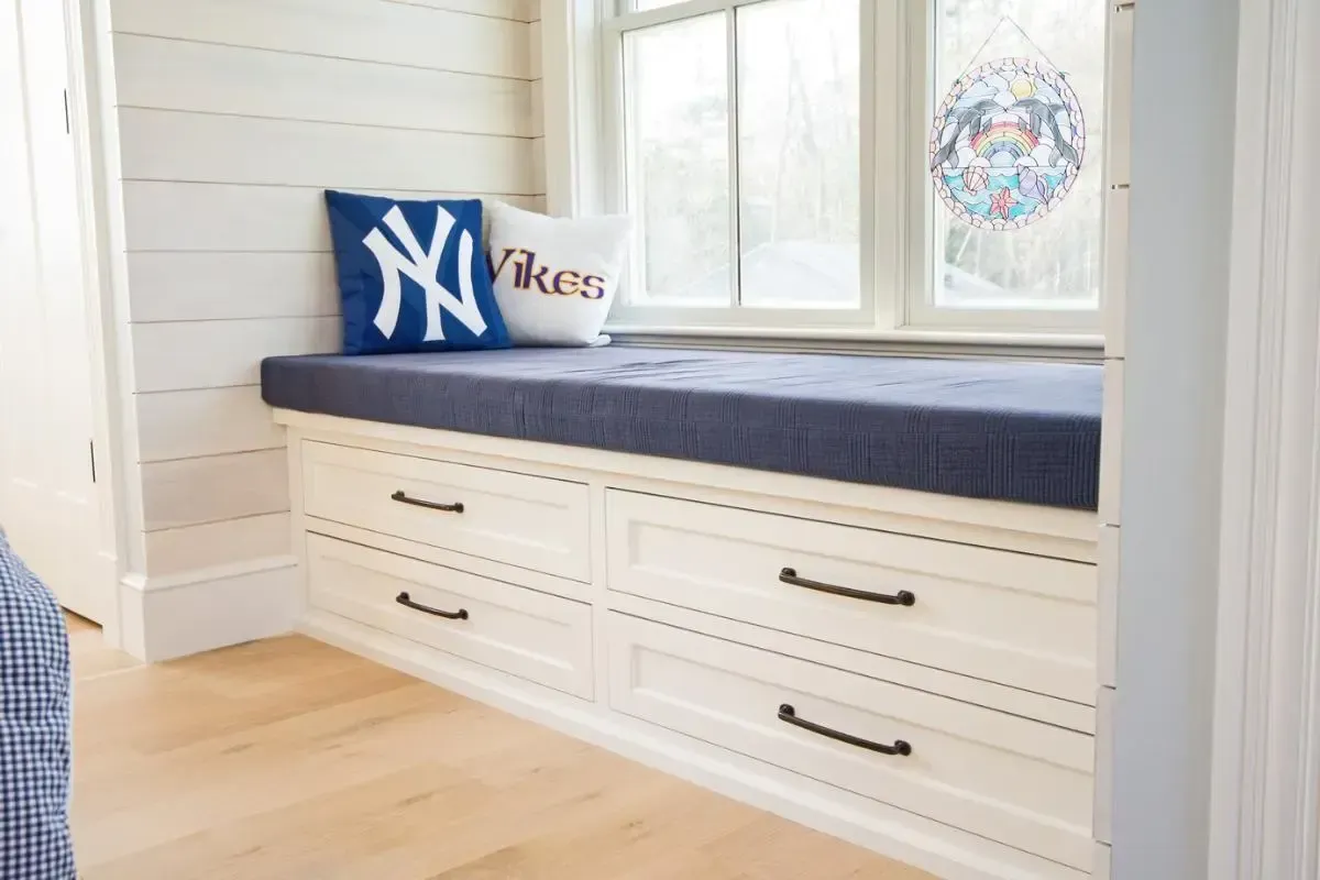 custom built in window seat with a blue cushion and drawers below.