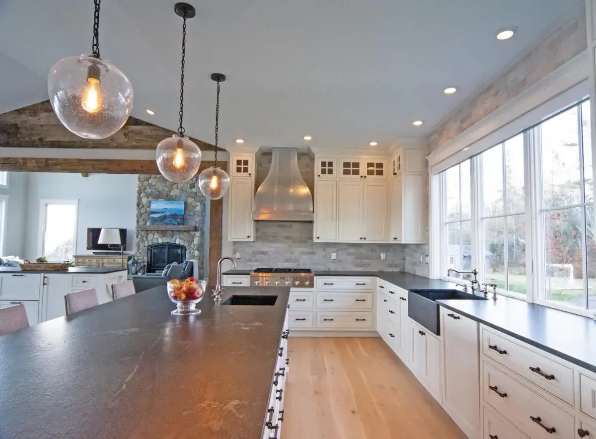 A kitchen with white cabinets and black counter tops