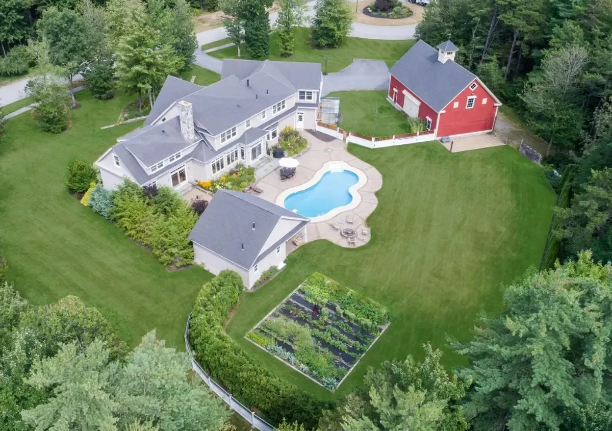 An aerial view of a large house with a pool and a red barn