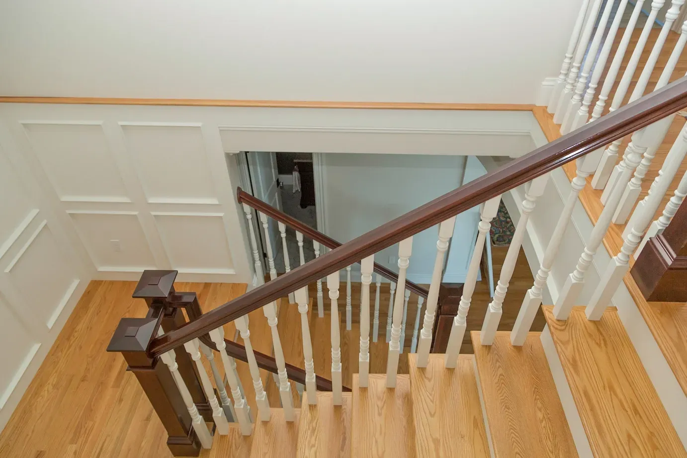 An aerial view of a wooden staircase with a white railing.