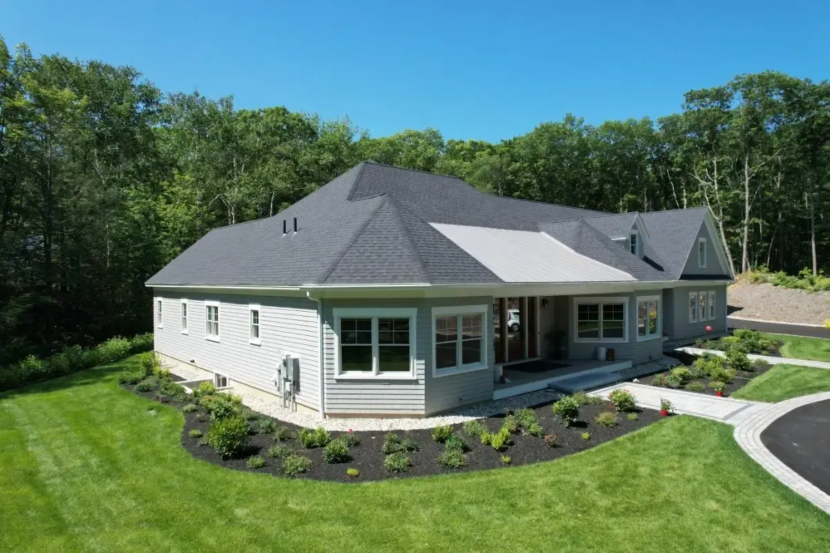 An aerial view of a large white house with a gray roof surrounded by trees.