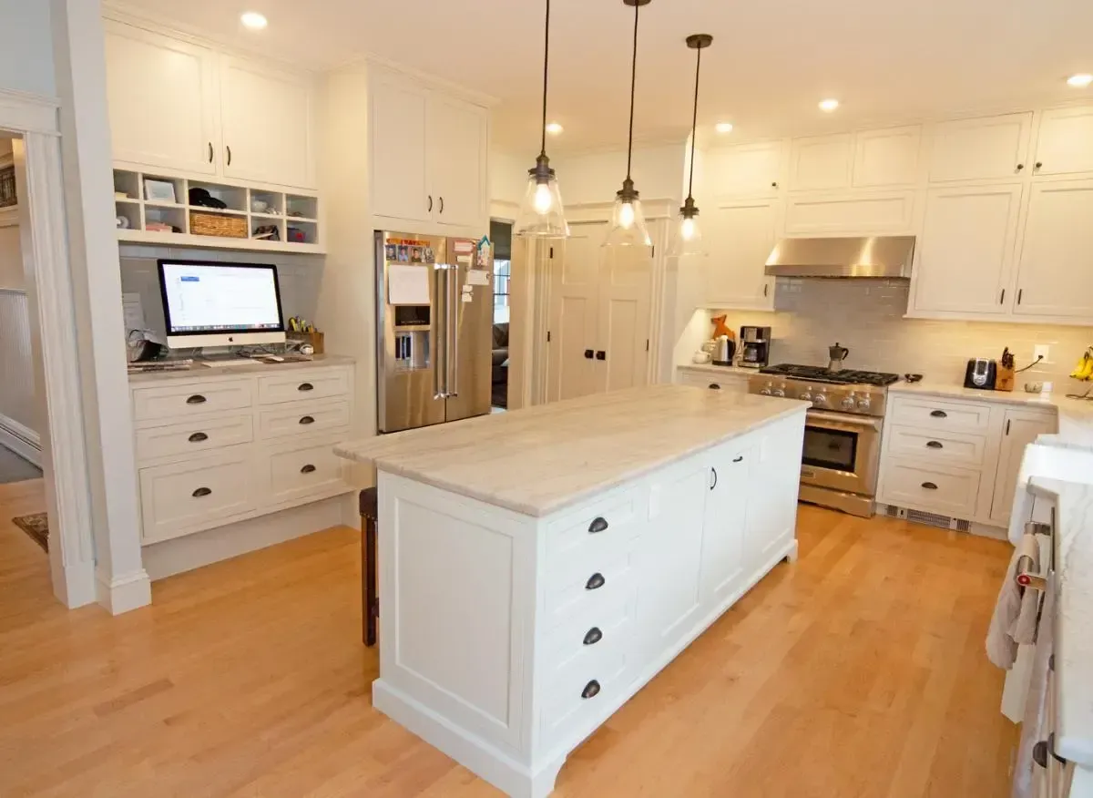kitchen island with light tan granite countertops white cabinets and hardwood floor.