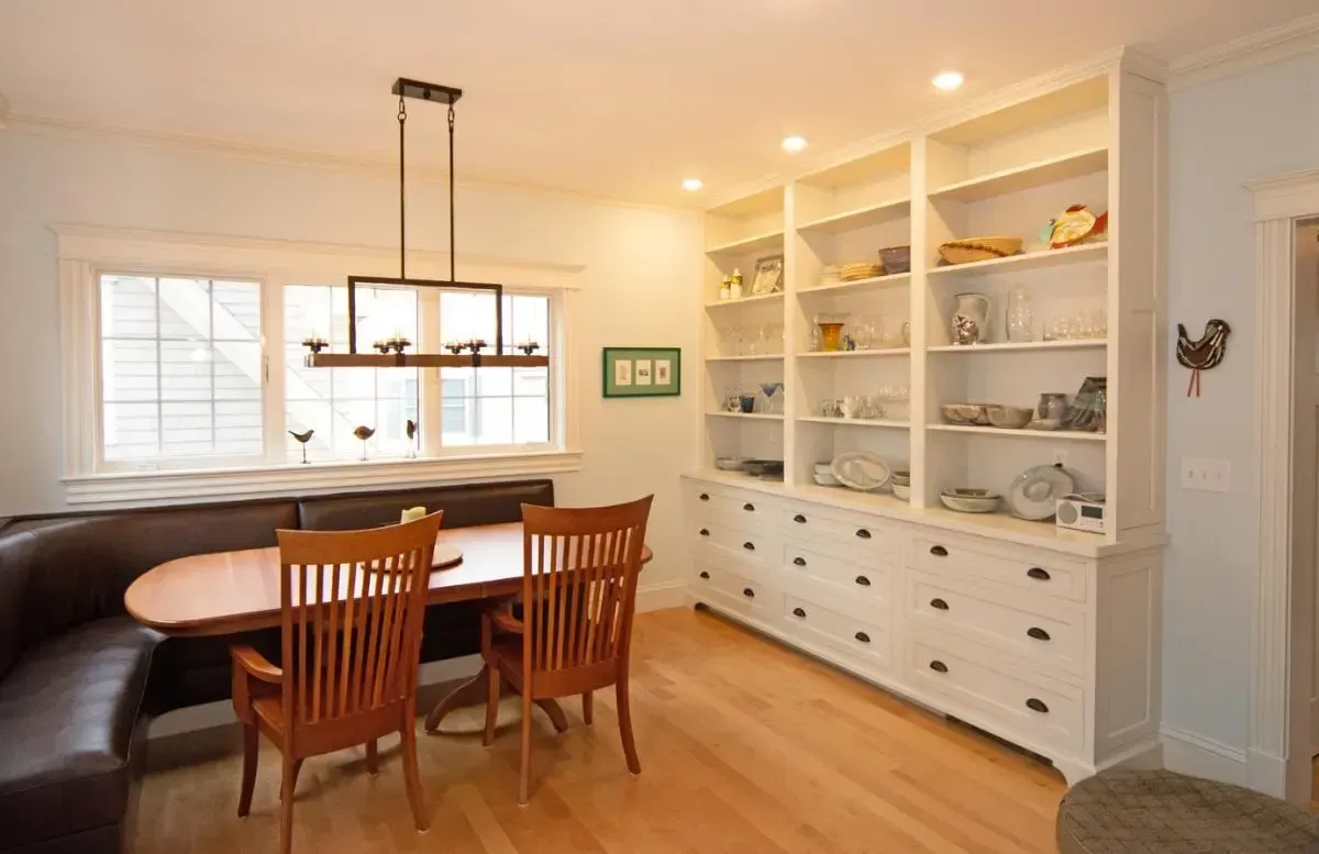 A dining room with a table and chairs and lots of shelves