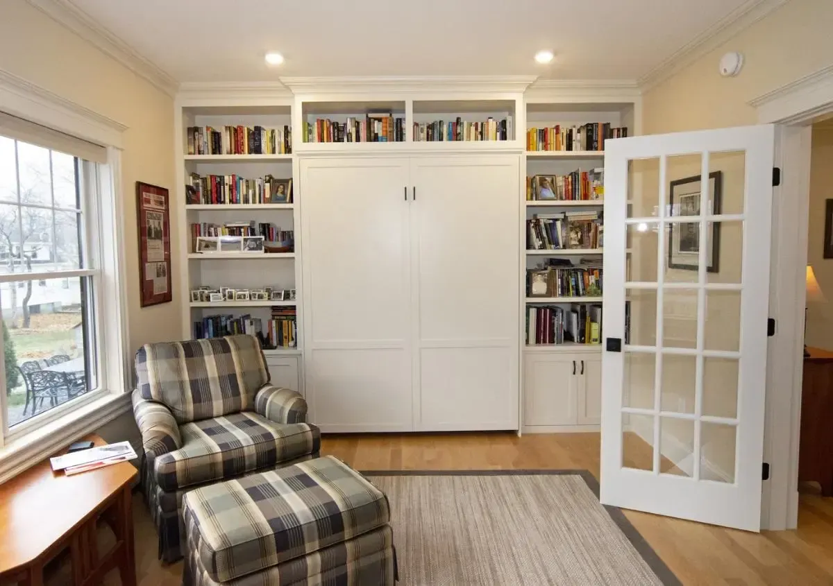 A living room with a chair and ottoman and bookshelves