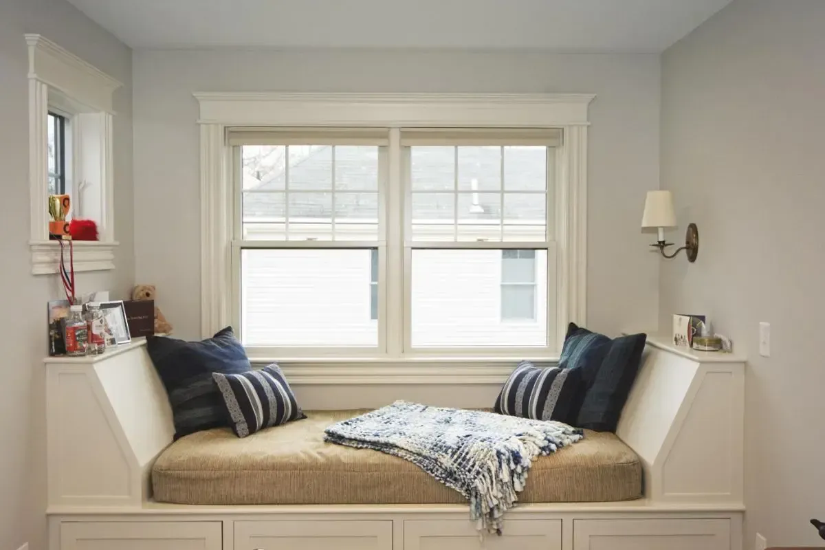 A window seat with a bed and pillows in front of a window.