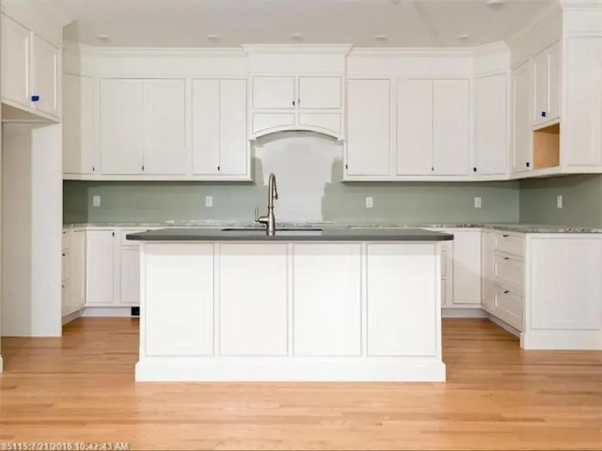 A kitchen with white cabinets and a large island in the middle.