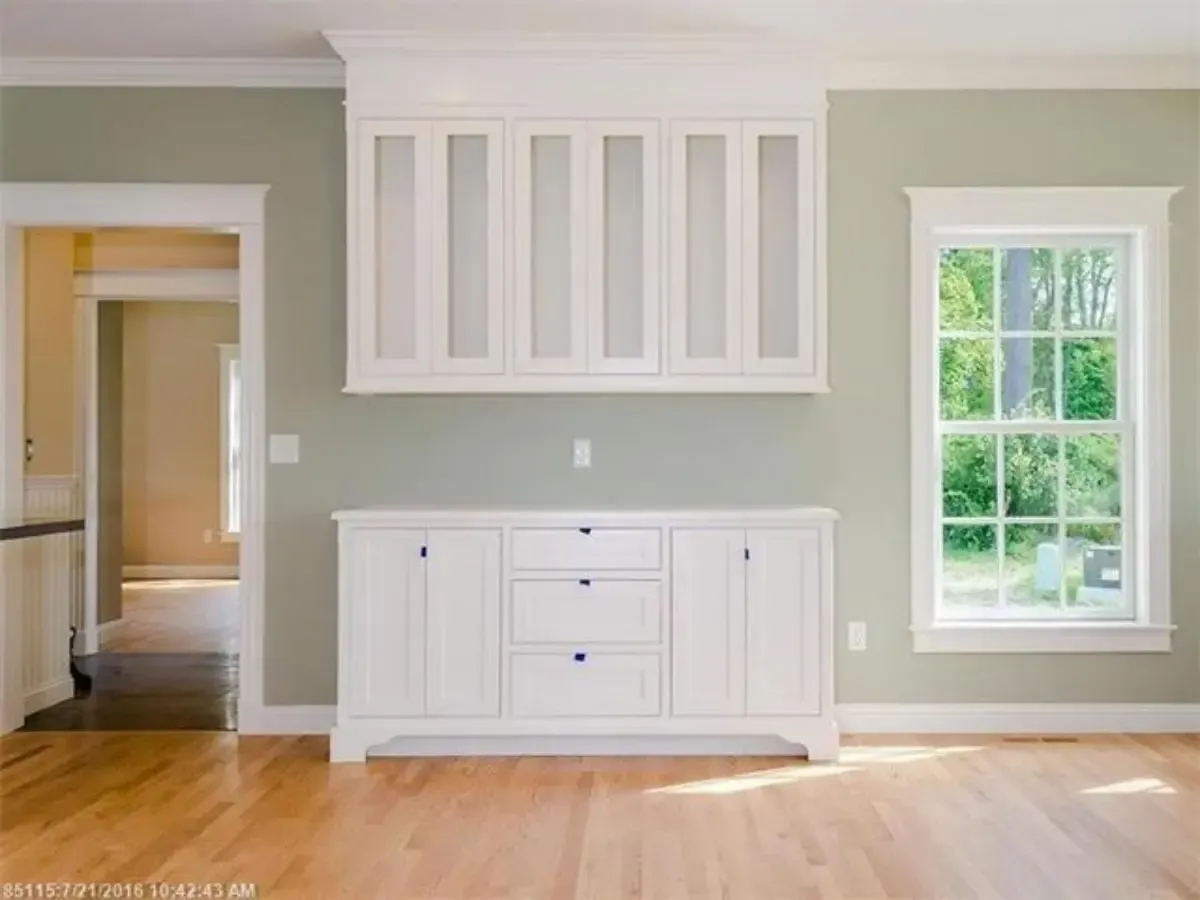 An empty room with white cabinets and a window