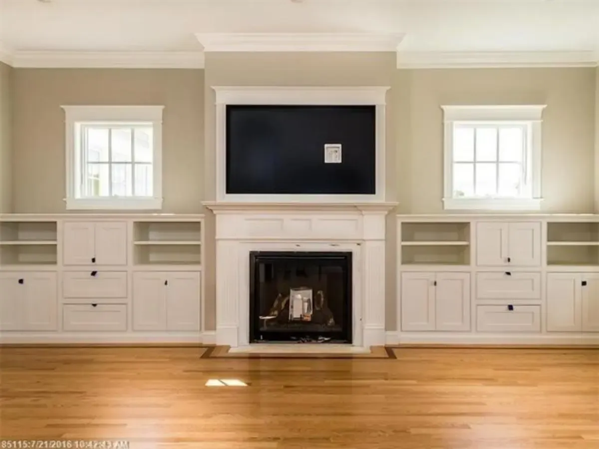 A living room with a fireplace and built in shelves