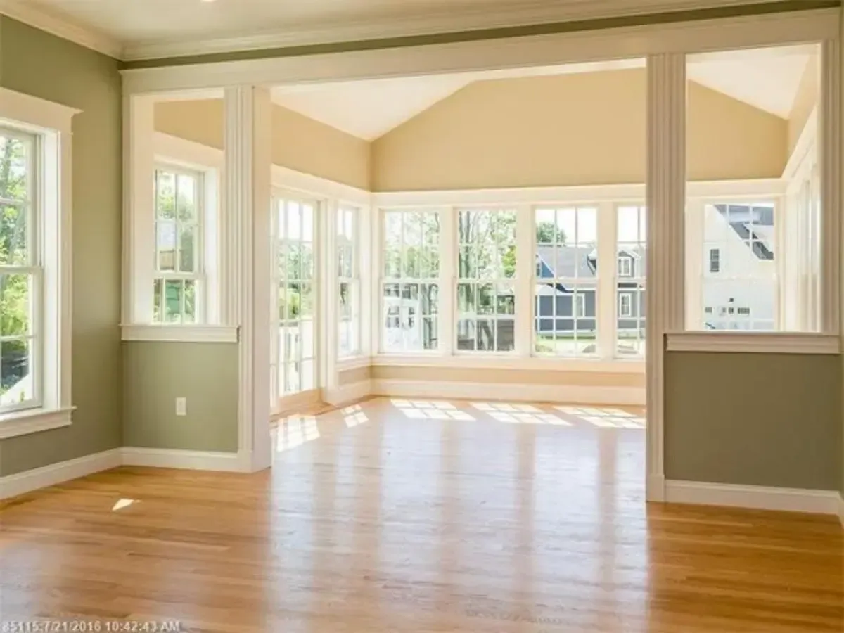 An empty room with lots of windows and hardwood floors