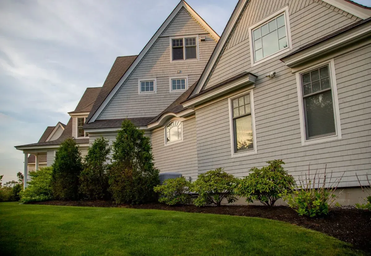 A large house with a lot of windows and a lush green lawn in front of it.