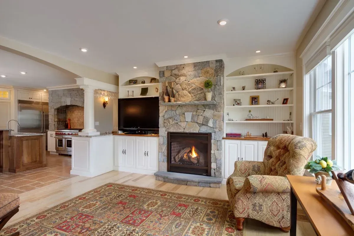 A living room with a fireplace , chair , rug and television.