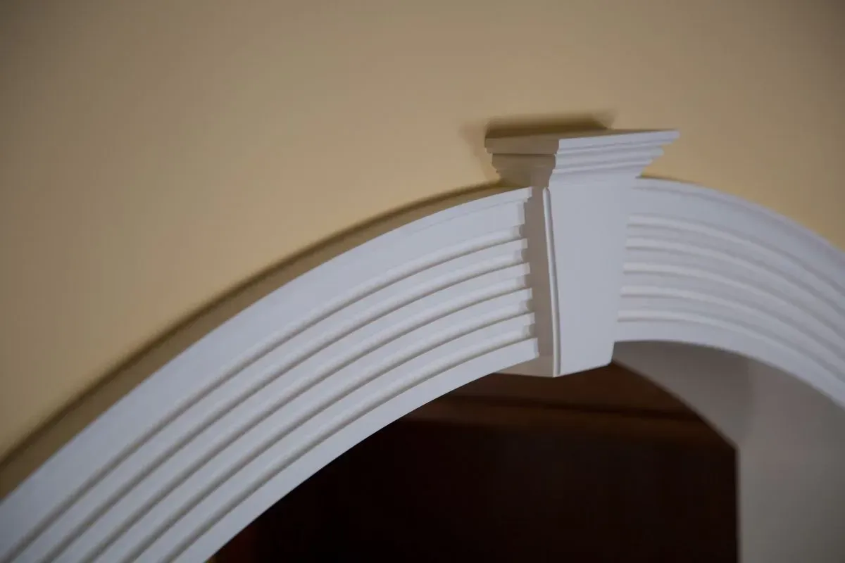 A white arch with a yellow wall in the background