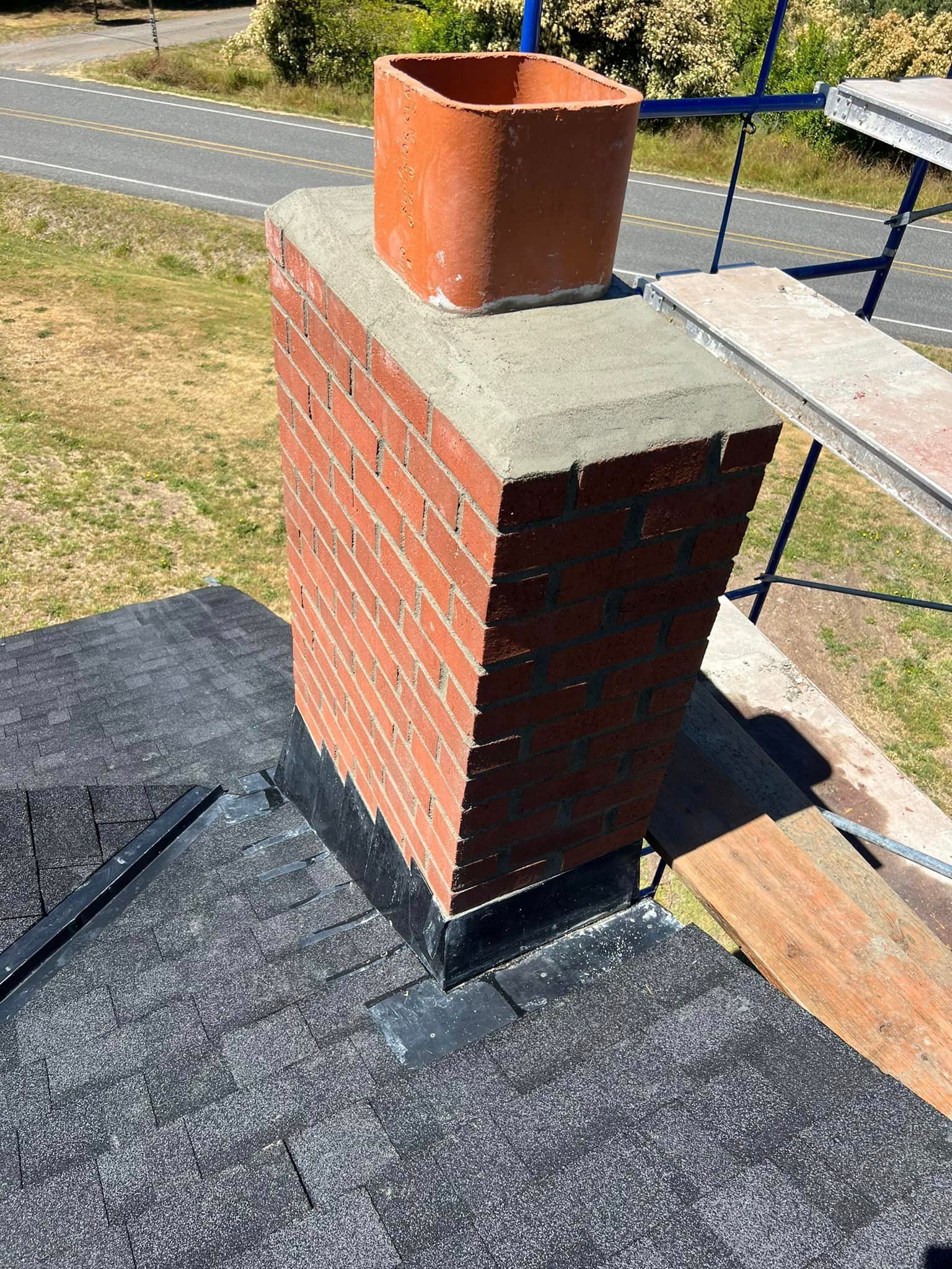 A brick chimney is sitting on top of a roof.