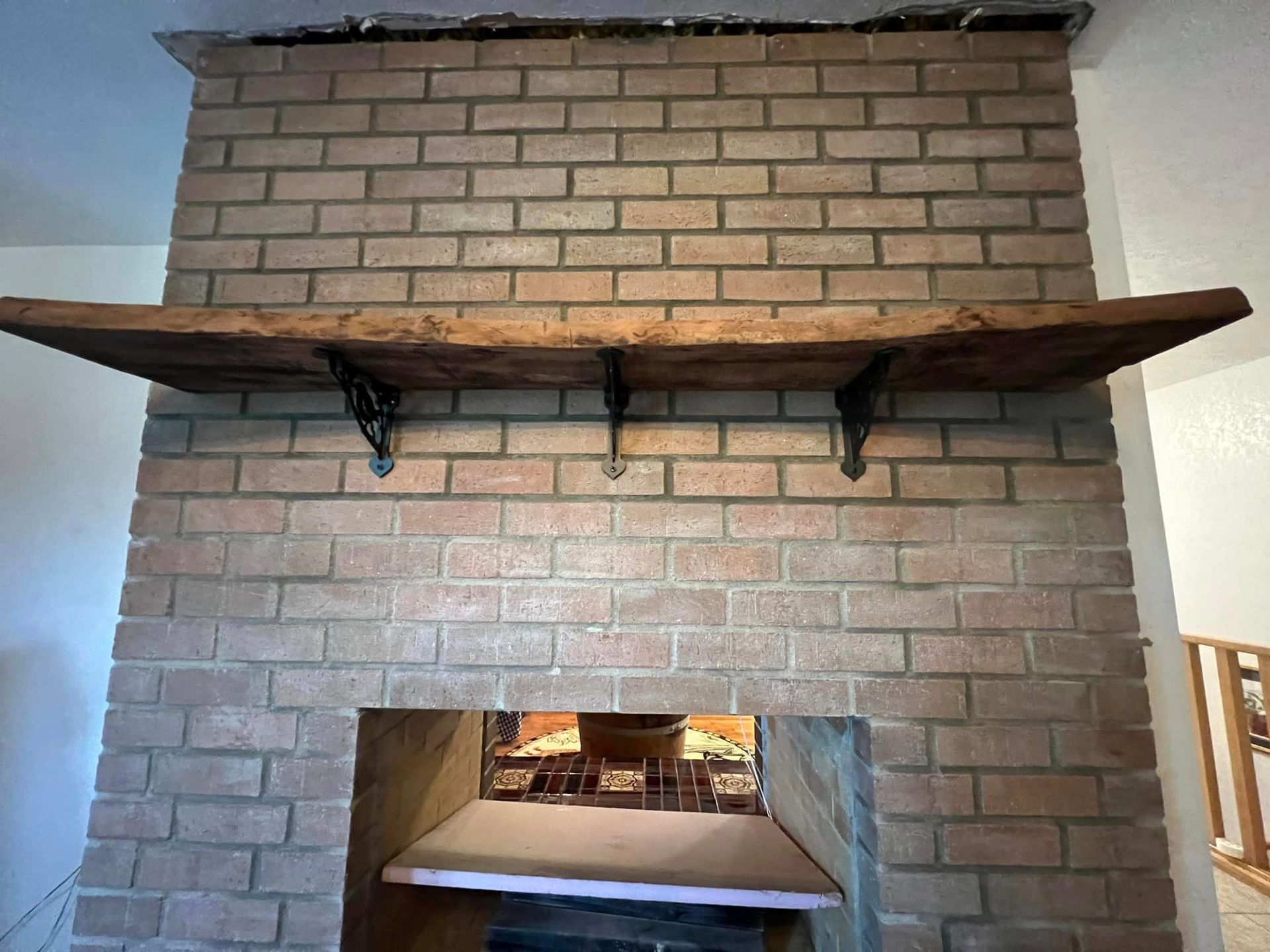 A brick fireplace with a wooden shelf above it.