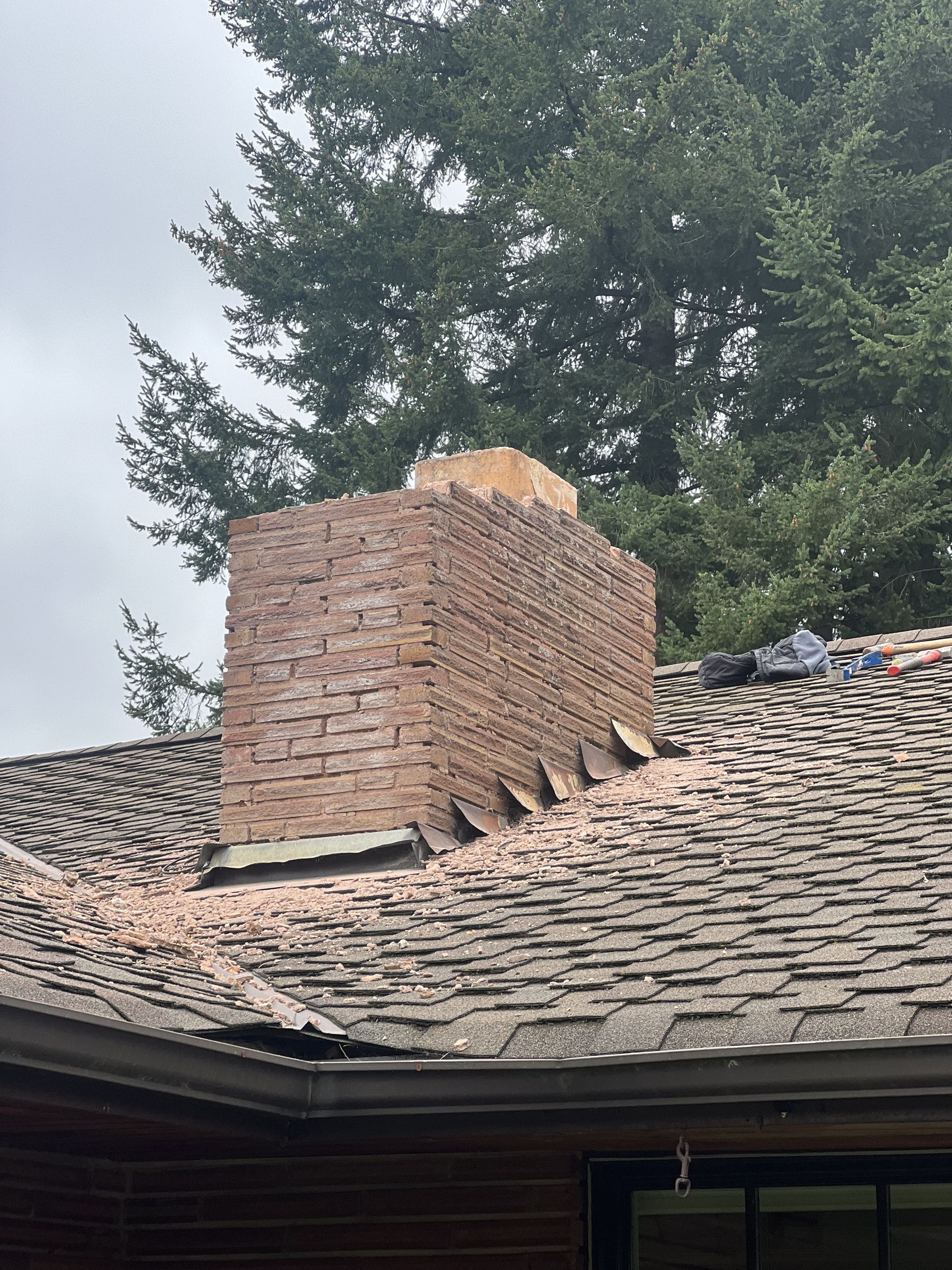 A brick chimney is sitting on top of a roof.