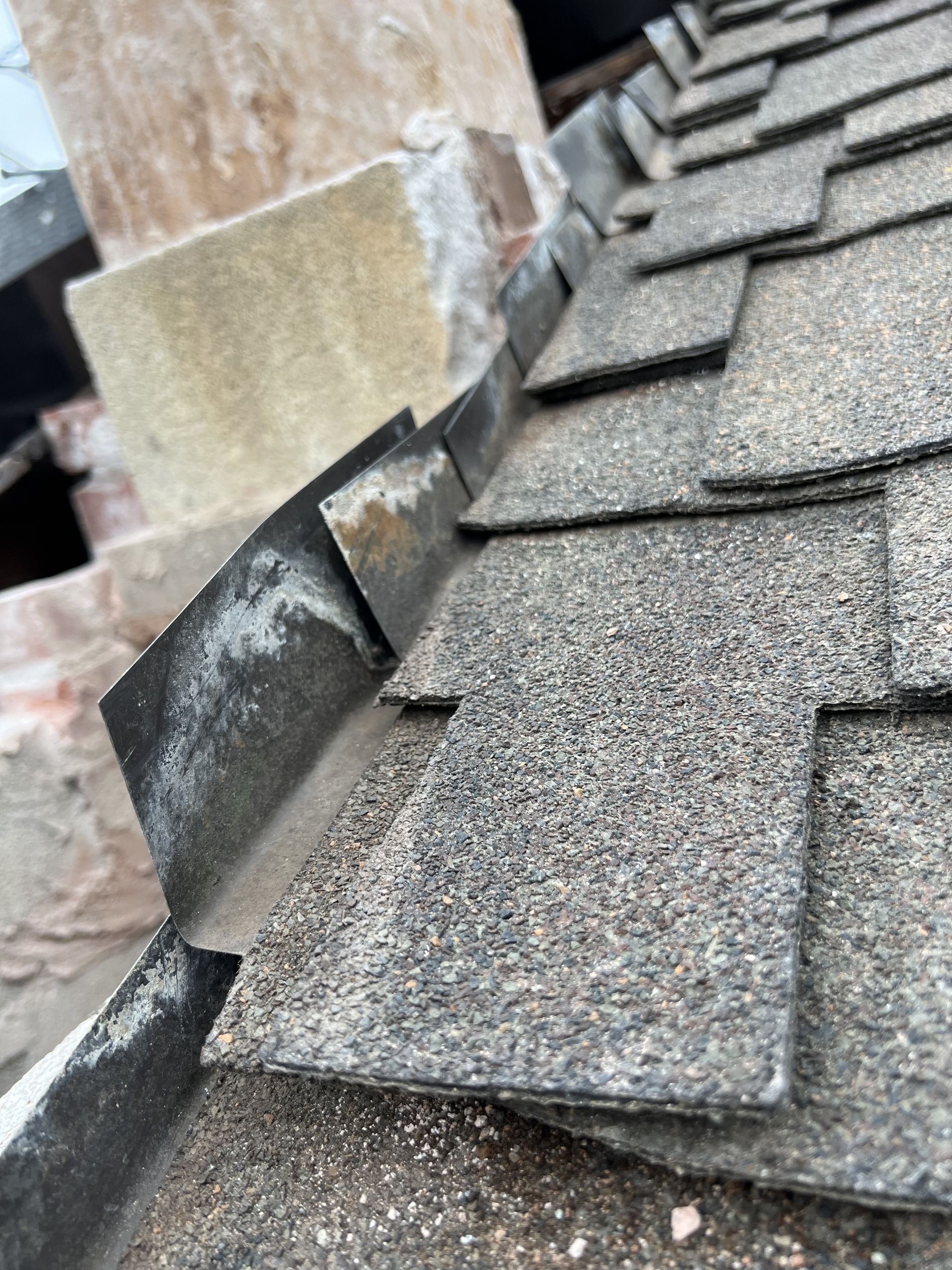 A close up of a roof with shingles and a chimney.
