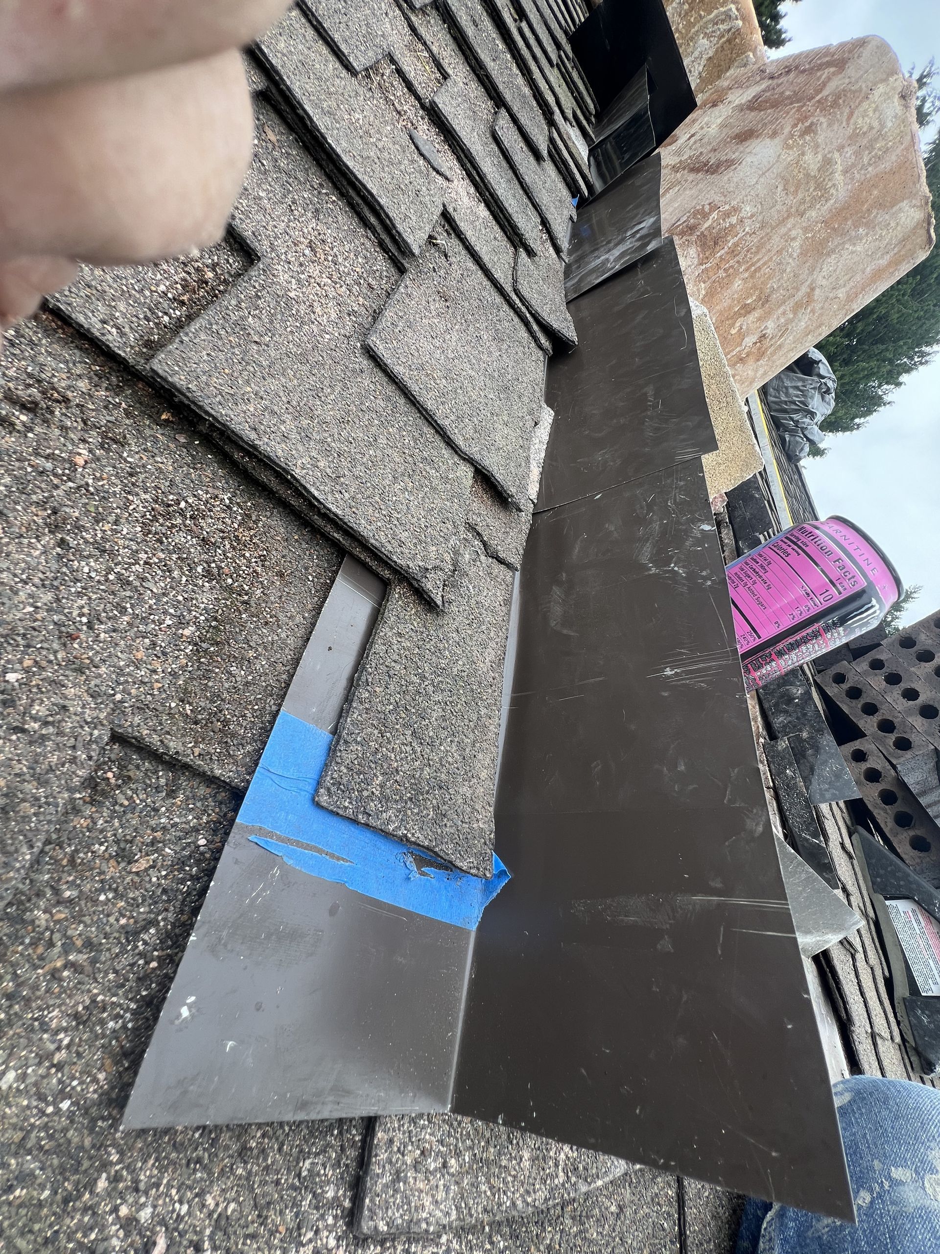 A person is holding a piece of metal on top of a roof.