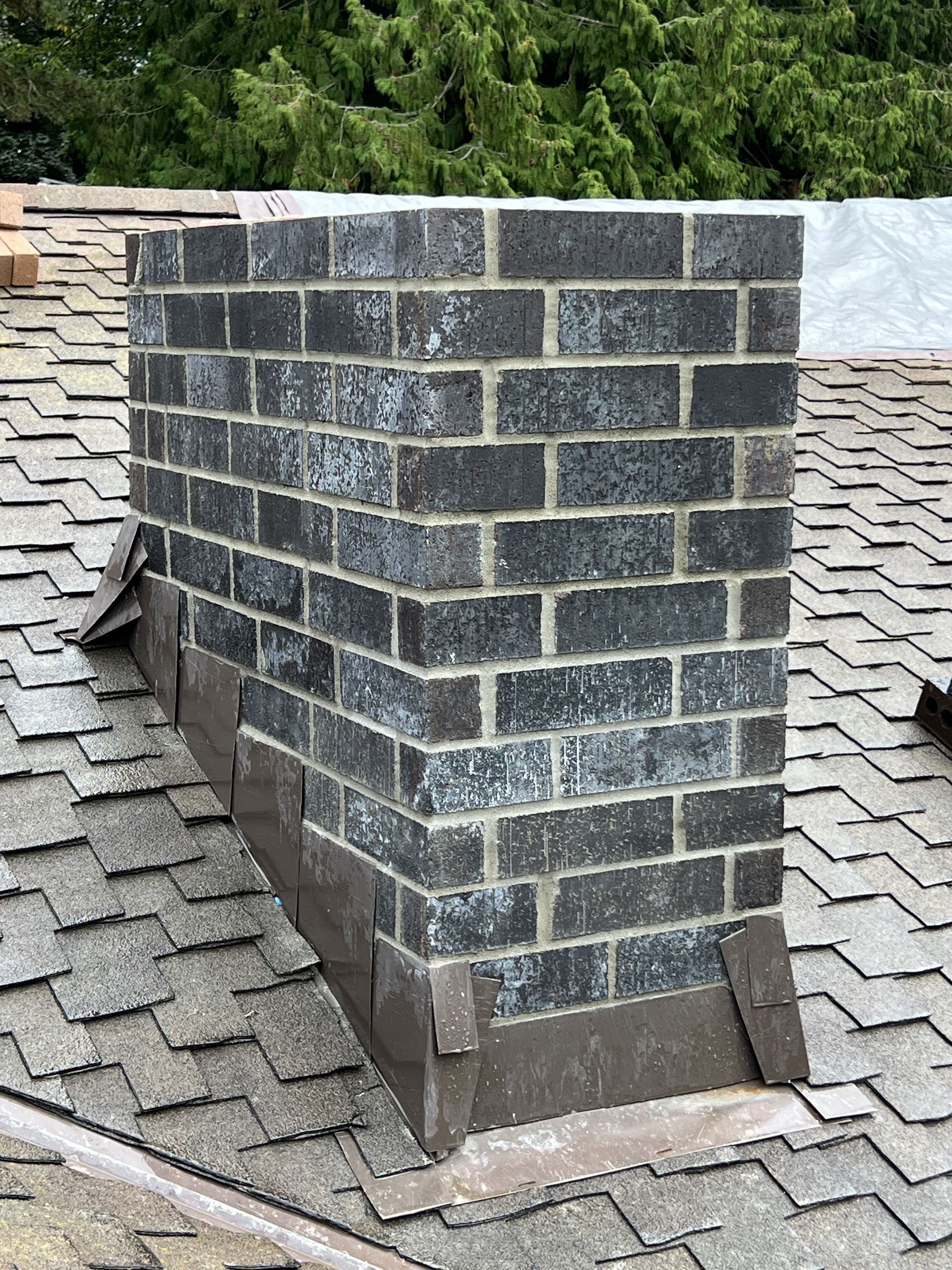 A brick chimney is sitting on top of a roof.