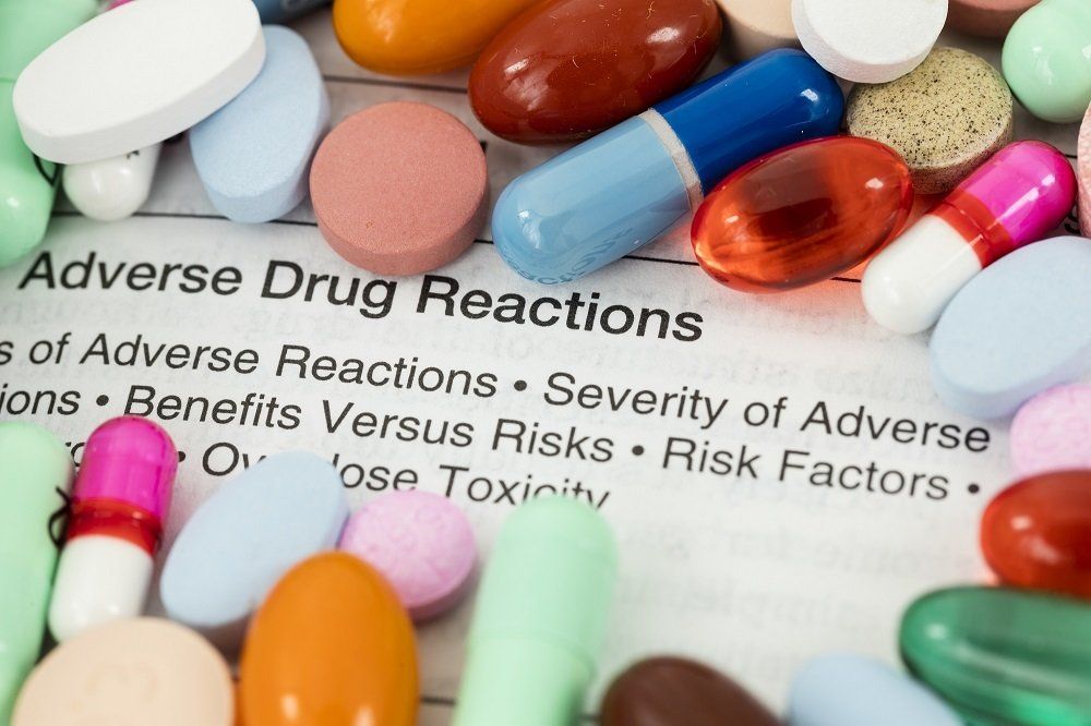 a list of adverse drug reactions is surrounded by pills and capsules