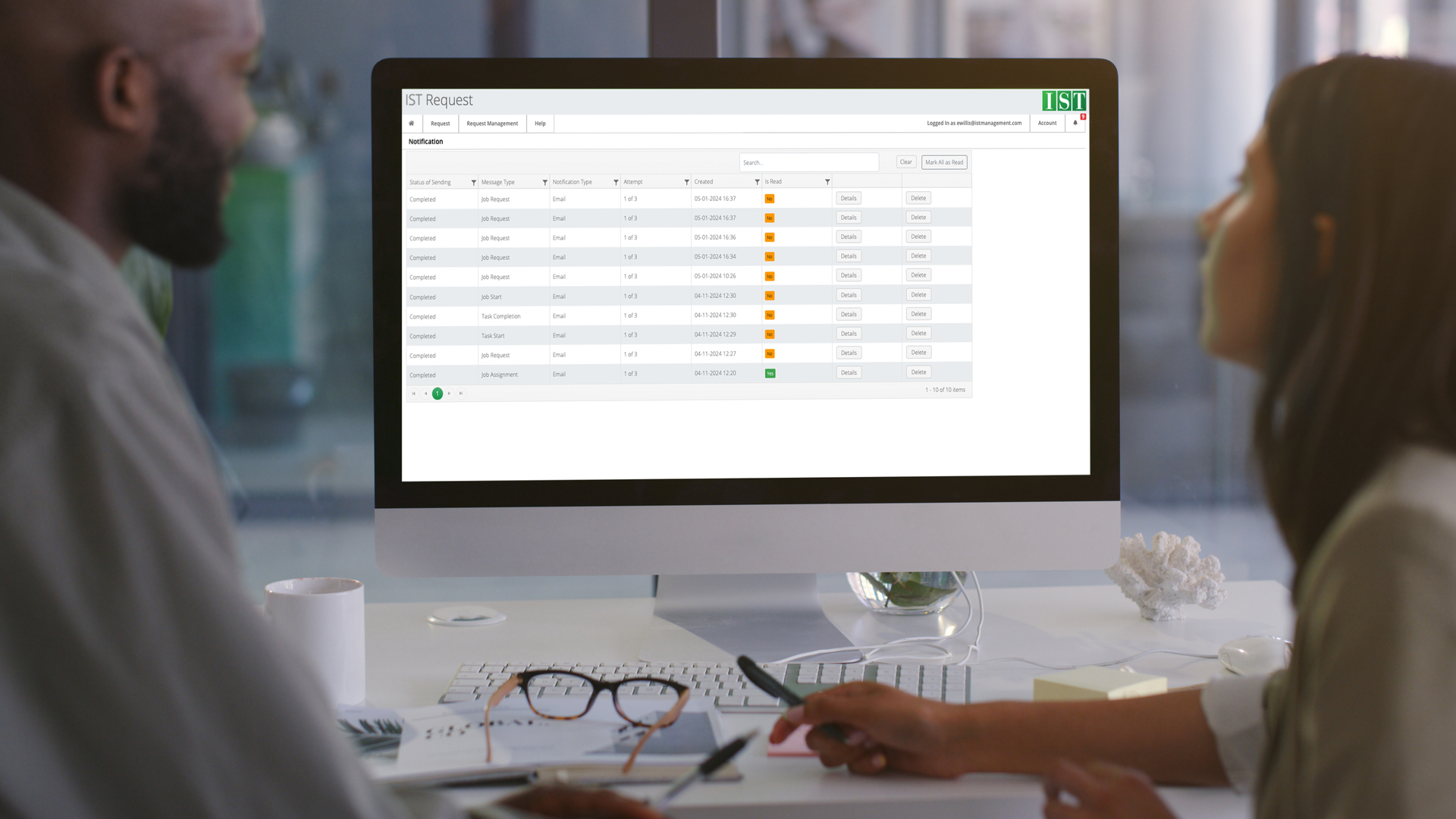 Coworkers sit at a computer and discuss details of the tasks given to them managed by IST Request