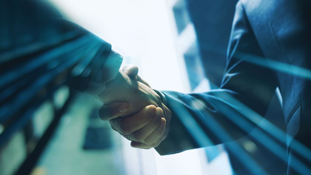 Lawyers shake hands with light streaming over their hands