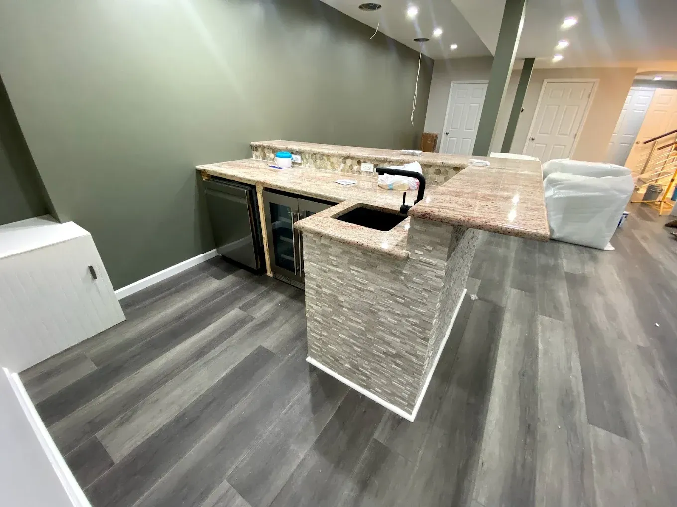 A kitchen with a sink and a refrigerator in a basement.