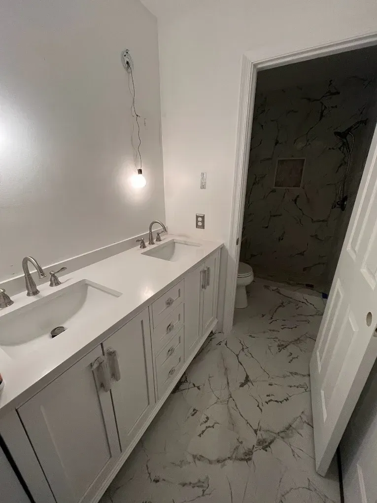 A bathroom with two sinks , a toilet and a shower.