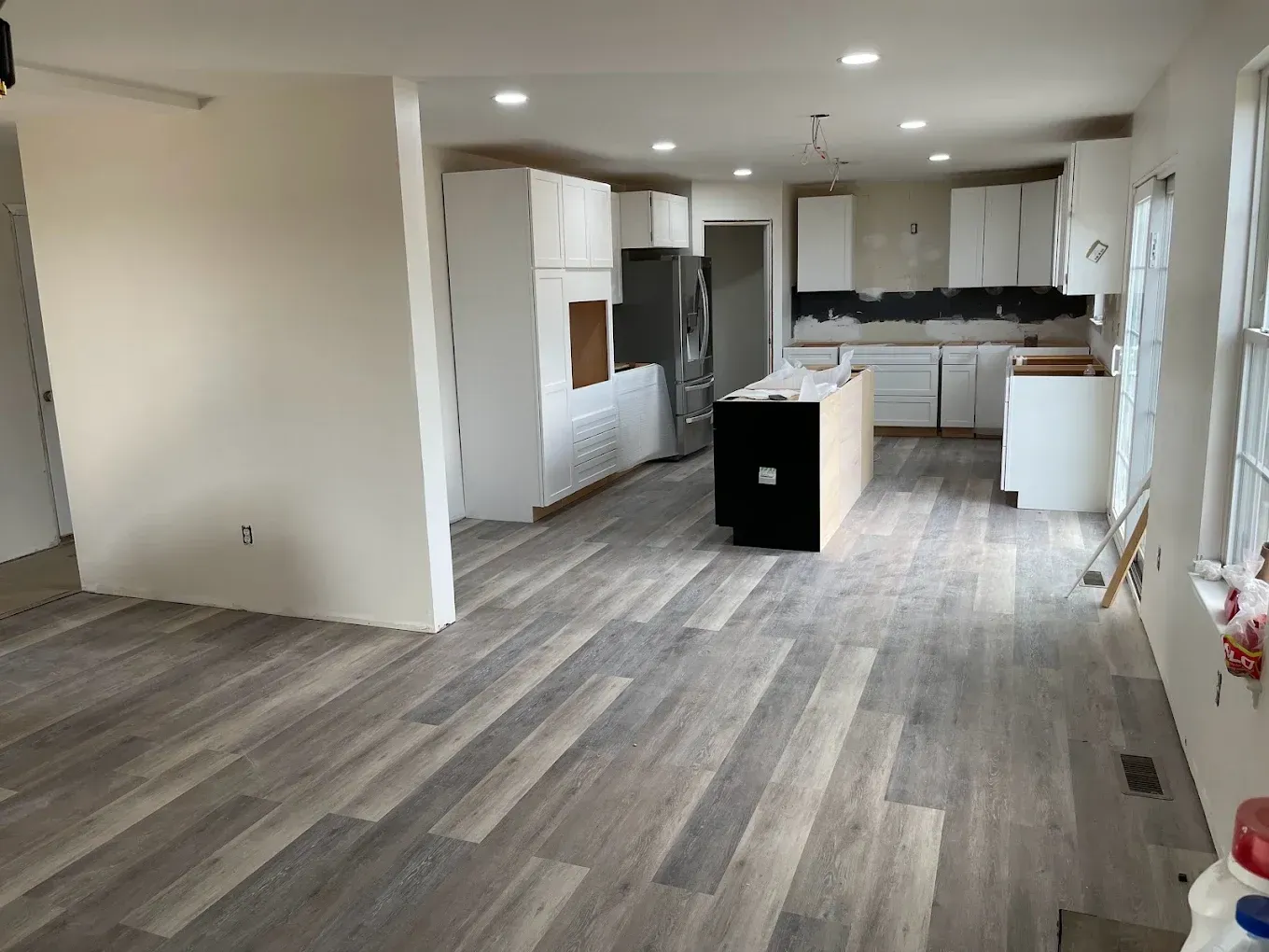 A kitchen with hardwood floors and white cabinets is being remodeled.