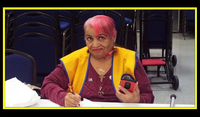 A woman with pink hair is writing on a piece of paper