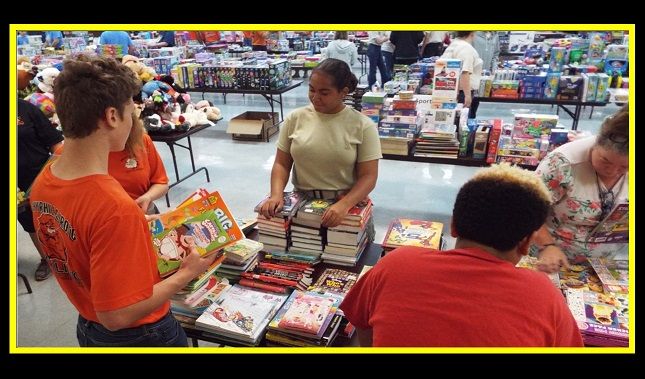 A group of people are standing around a table in a store looking at books.