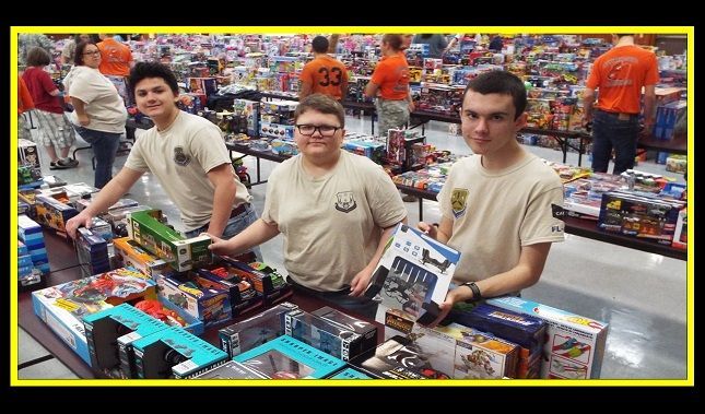 A group of young men are standing in front of a table full of toys.
