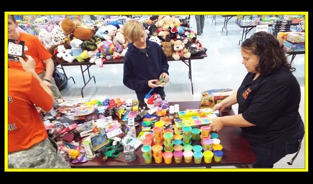 A group of people are gathered around a table full of toys