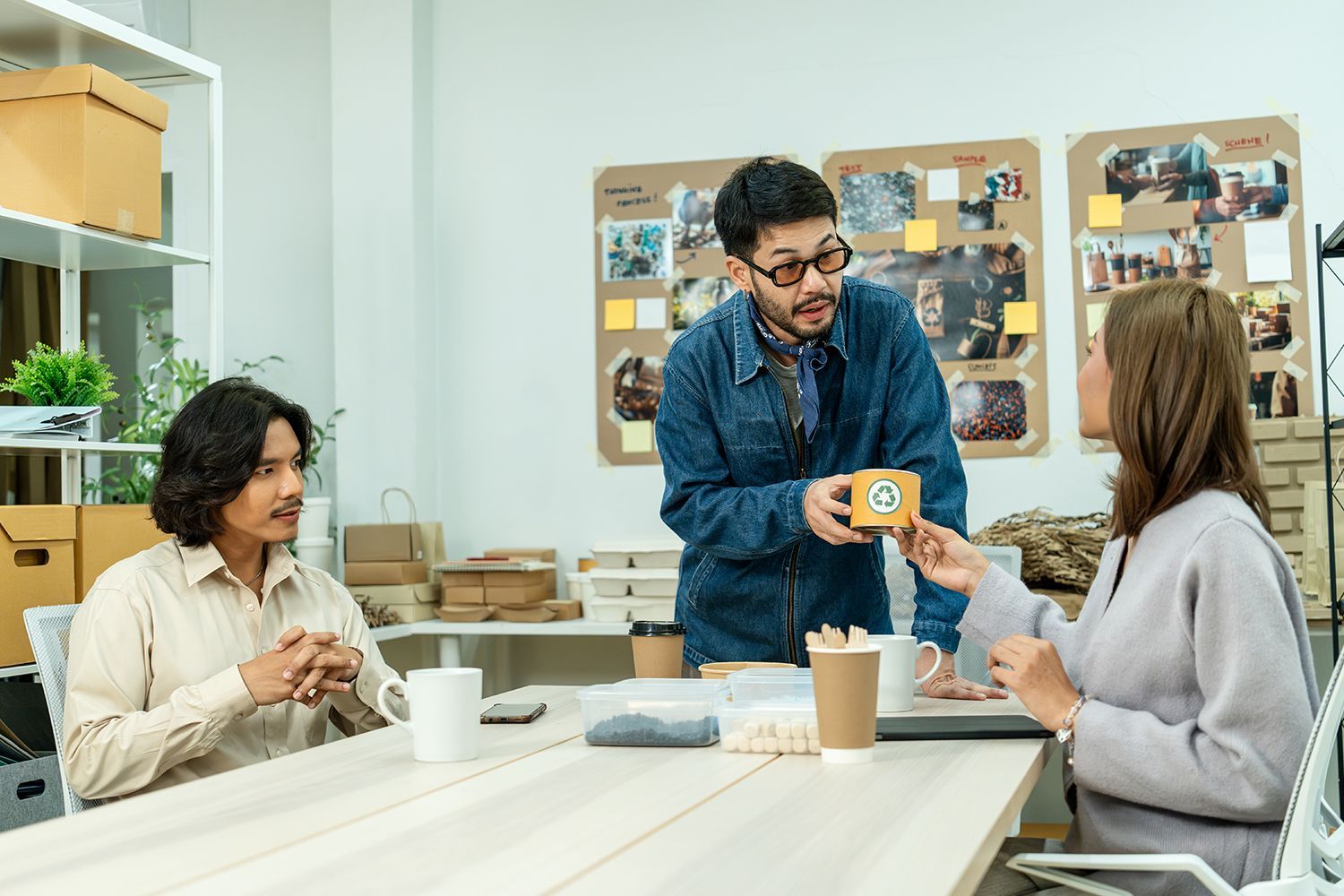 Team discussing eco-friendly packaging prototype in modern workspace for sustainable product design.