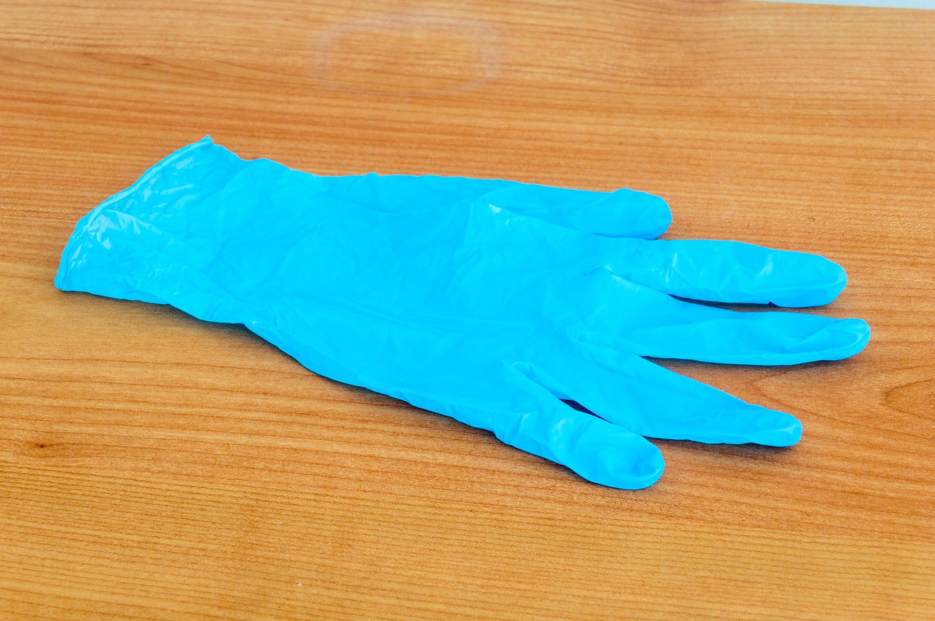 Blue nitrile glove on a wooden surface.